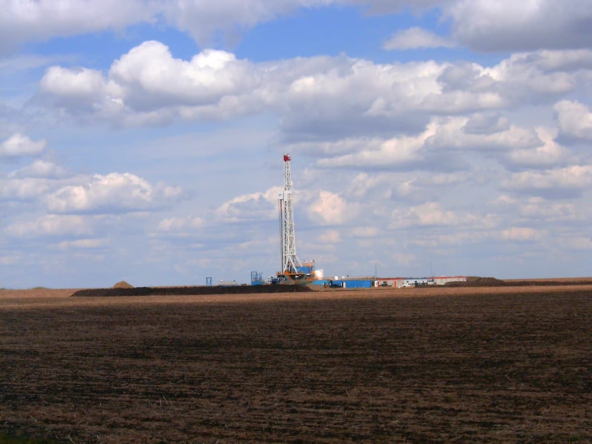 Oil and gas drilling well in Alberta Canada with rig infrastructure and equipment visible against open sky